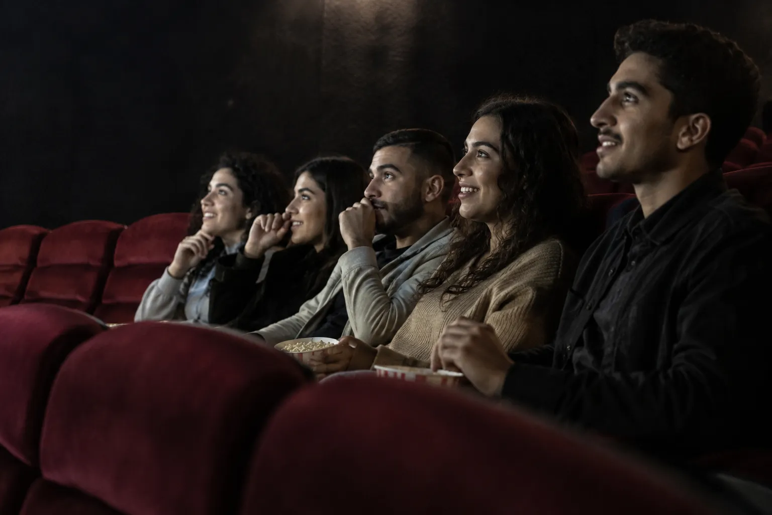 Illustration : des amis partagent un moment de cinéma dans une salle aux fauteuils bordeaux.